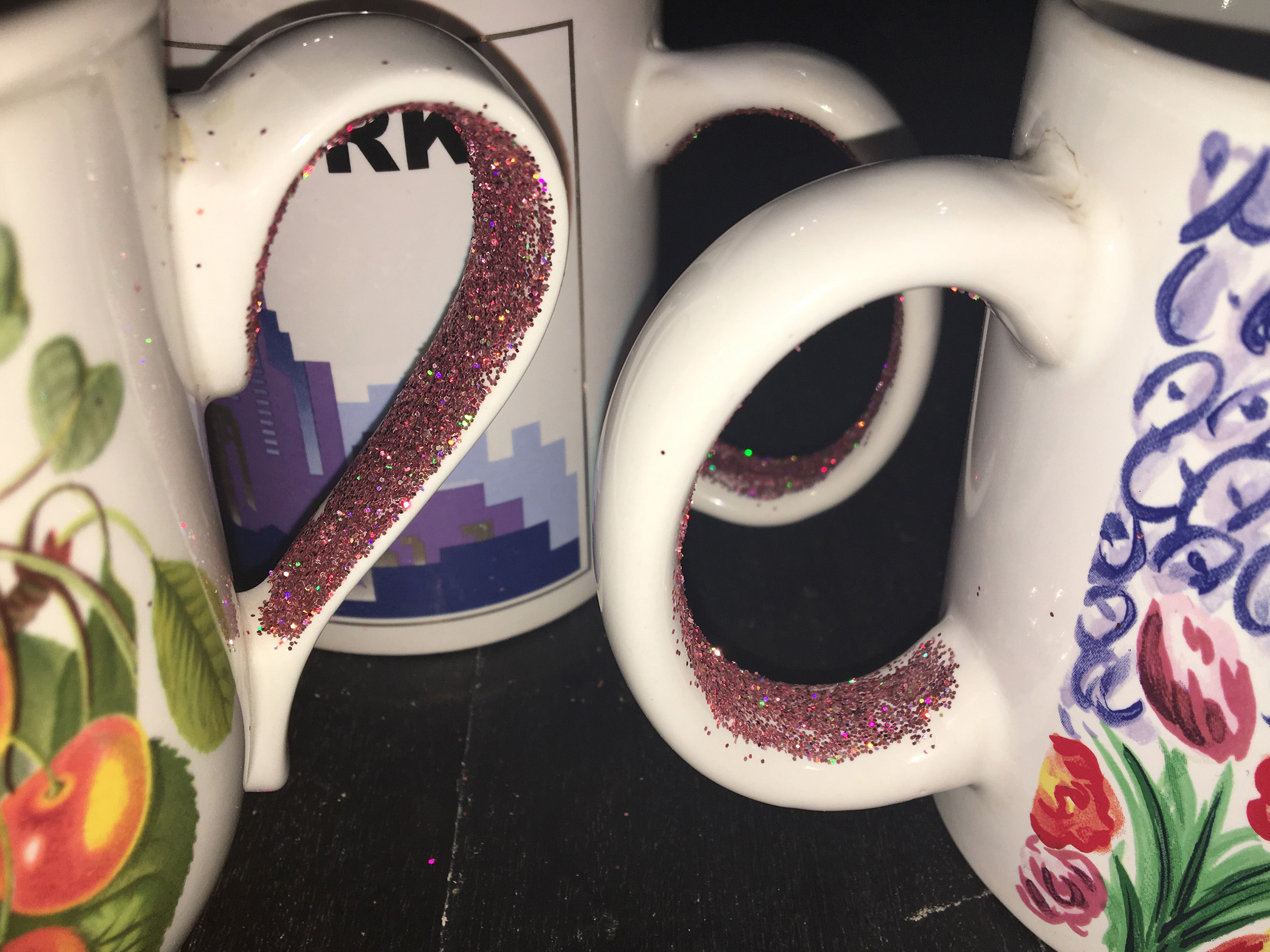 Trois mugs sont posés sur une table. On voit que des paillettes sont collées à l'intérieur des hanses. Photo avec flash qui fait plus ressortir les pailletes qui sont holographiques.